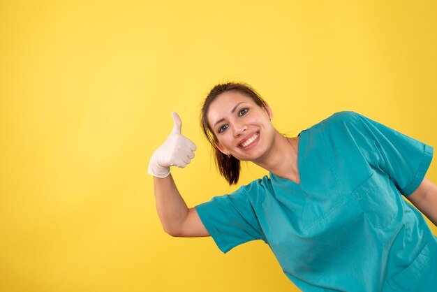 Vue de face femme médecin dans des gants médicaux sur fond jaune