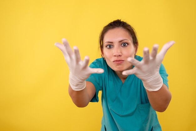Vue de face femme médecin dans des gants médicaux sur fond jaune