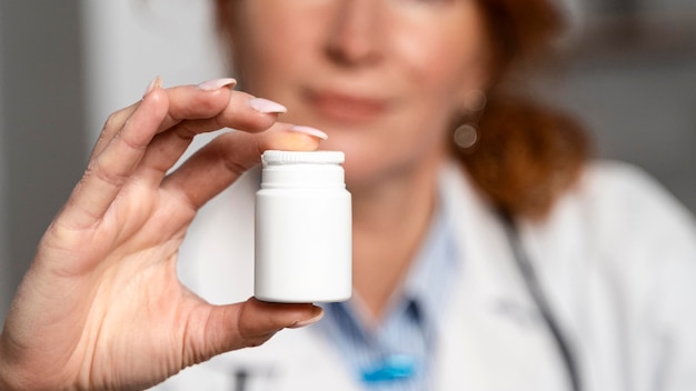 Photo gratuite vue de face de la femme médecin défocalisé tenant une bouteille de médicament