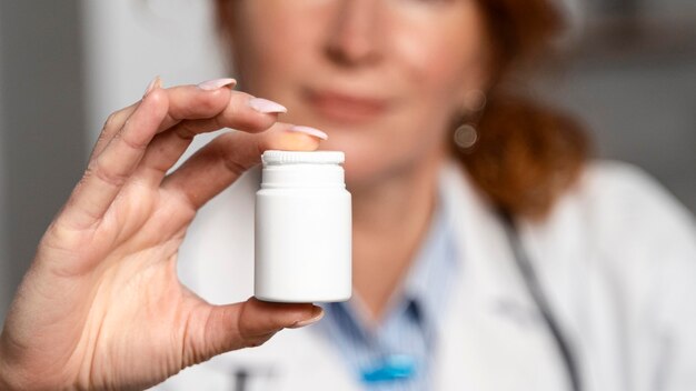 Vue de face de la femme médecin défocalisé tenant une bouteille de médicament