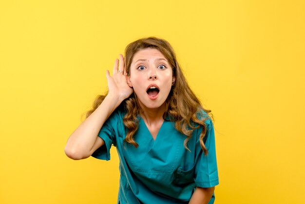 Vue de face de la femme médecin à l'écoute sur le mur jaune