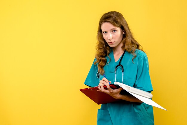 Vue de face femme médecin écrit des notes sur l'espace jaune