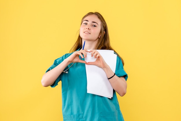Vue de face femme médecin envoi d'amour sur fond jaune infirmière d'hôpital virus de la santé