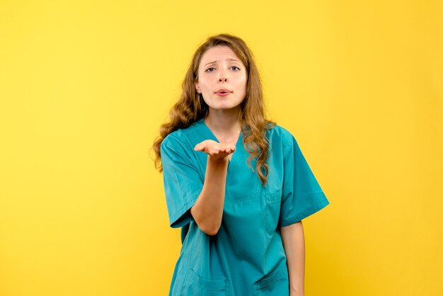 Vue de face de la femme médecin envoyant l'amour sur le mur jaune