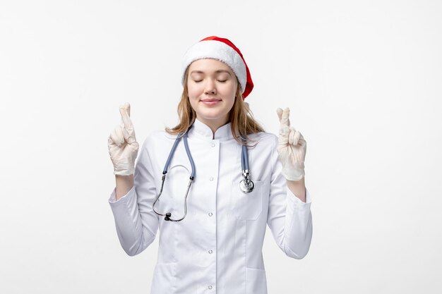 Vue de face d'une femme médecin espérant sur un mur blanc