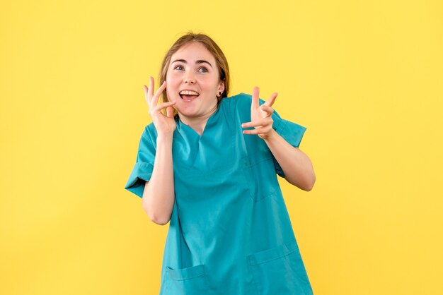 Vue de face femme médecin excité sur fond jaune medic émotion virus de la santé de l'hôpital