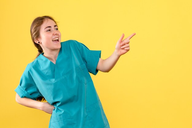 Vue de face femme médecin excité sur fond jaune virus de couleur de l'hôpital de la santé