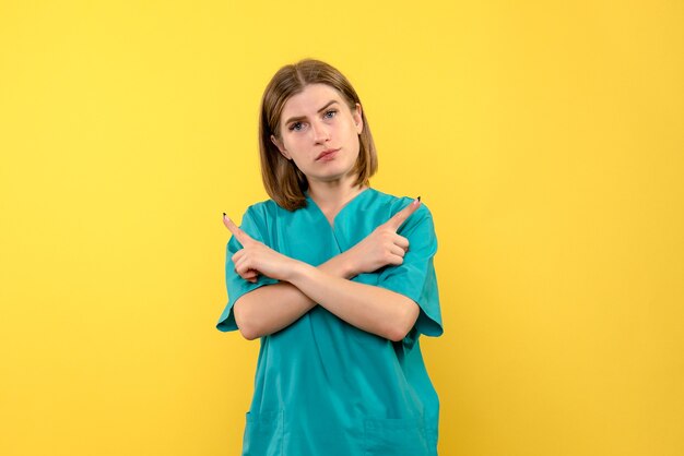 Vue de face femme médecin avec une expression calme sur l'espace jaune