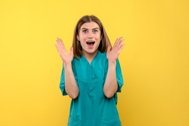 Vue de face femme médecin avec expression excitée sur l'espace jaune