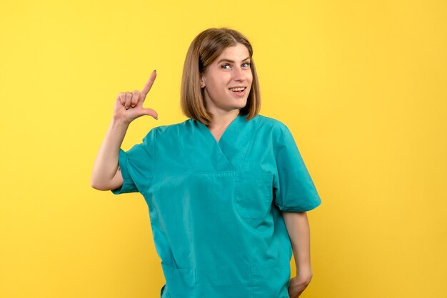 Vue de face femme médecin avec expression excitée sur l'espace jaune