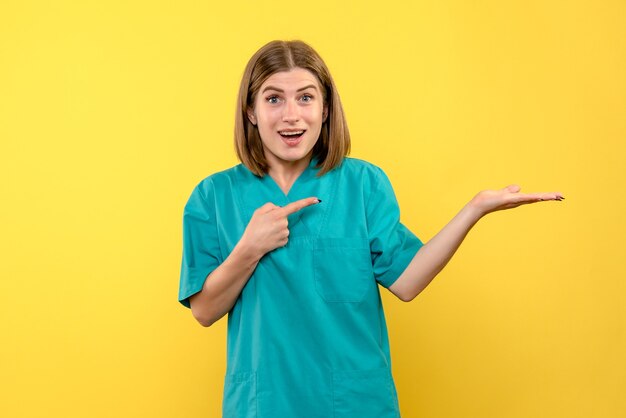 Vue de face de femme médecin avec expression excitée sur mur jaune