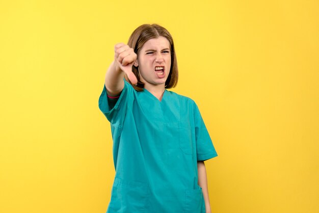 Vue de face femme médecin avec une expression mécontente sur l'espace jaune