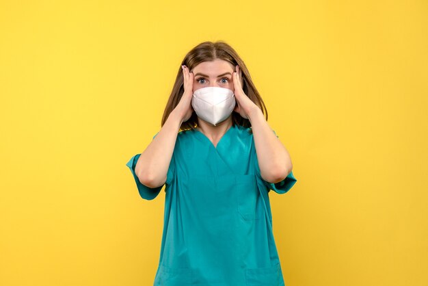 Vue de face de la femme médecin avec une expression stressée sur mur jaune