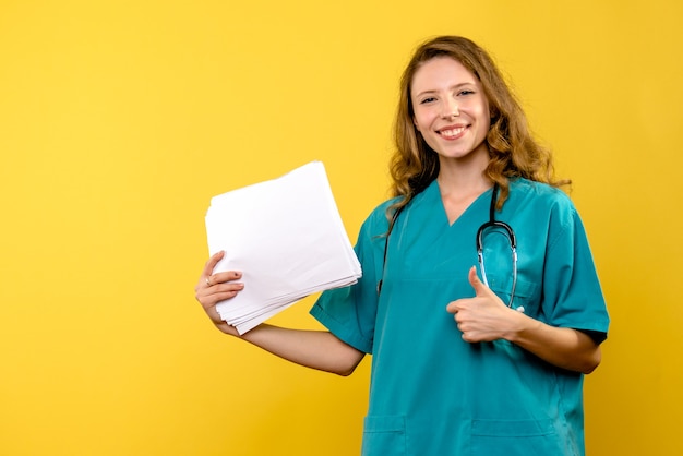 Vue de face femme médecin avec des fichiers sur l'espace jaune