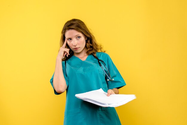 Vue de face femme médecin avec des fichiers sur l'espace jaune