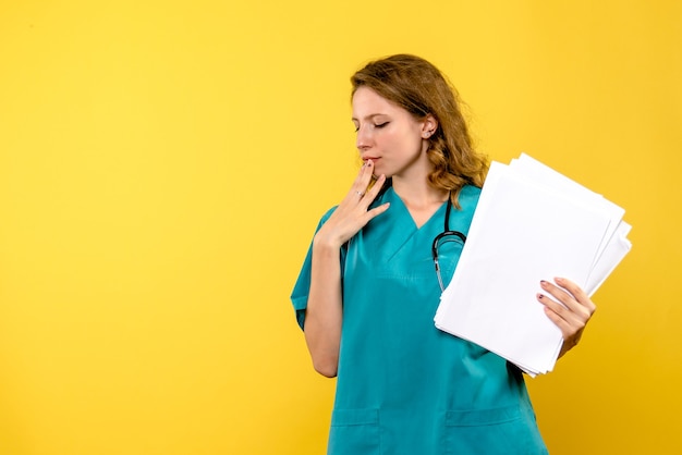 Vue de face femme médecin avec des fichiers pensant à l'espace jaune