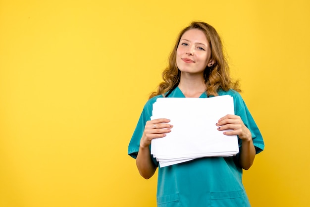 Vue de face femme médecin avec des fichiers sur le sol jaune émotion virus de l'hôpital médical