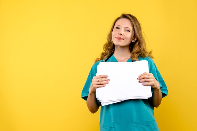 Vue de face femme médecin avec des fichiers sur le sol jaune émotion virus de l'hôpital médical