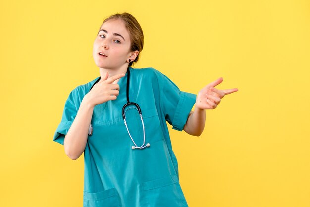 Vue de face femme médecin sur fond jaune émotion hôpital santé medic