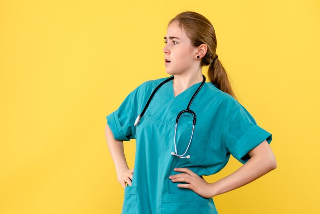 Vue de face femme médecin sur fond jaune émotion médical santé de l'hôpital