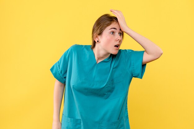 Vue de face femme médecin sur fond jaune émotions de santé de l'hôpital médical