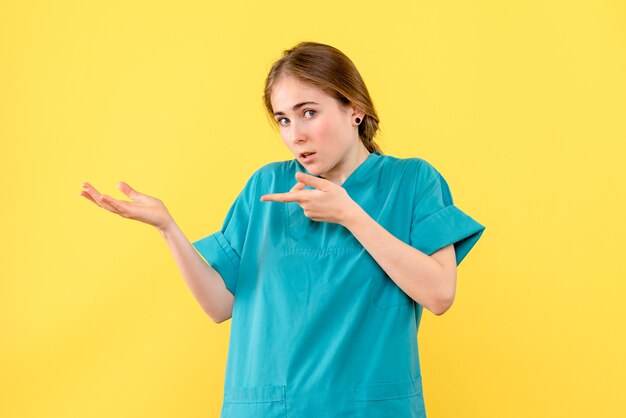 Vue de face femme médecin sur fond jaune médical émotion santé de l'hôpital