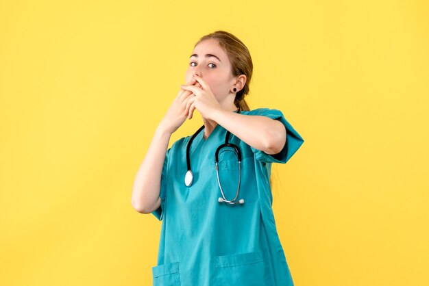 Vue de face femme médecin sur fond jaune médical hôpital émotion santé