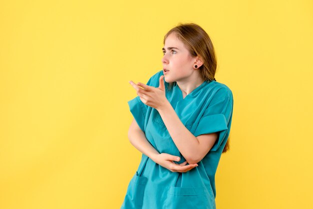 Vue de face femme médecin sur fond jaune virus de la santé de l'hôpital des émotions du médecin