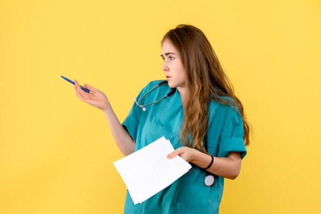 Vue de face femme médecin sur fond jaune virus de la santé hôpital infirmière émotion