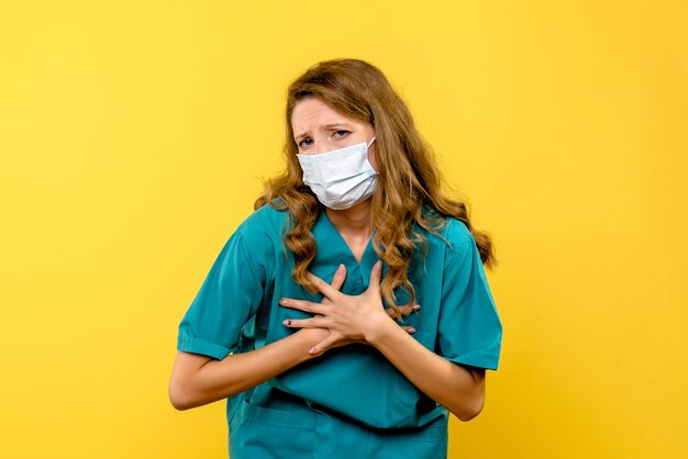 Vue de face femme médecin en masque sur espace jaune clair