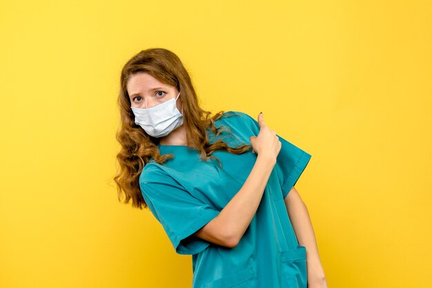 Vue de face femme médecin en masque sur espace jaune