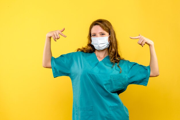 Vue de face femme médecin en masque sur espace jaune