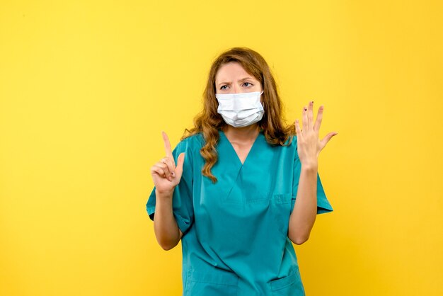 Vue de face femme médecin en masque sur espace jaune