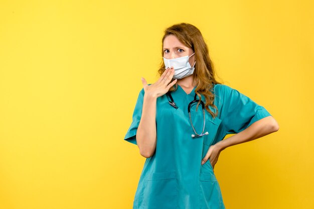 Vue de face femme médecin en masque sur espace jaune