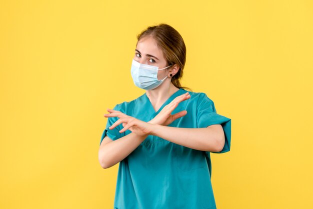 Vue de face femme médecin en masque sur fond jaune pandémie de l'hôpital de covid-santé