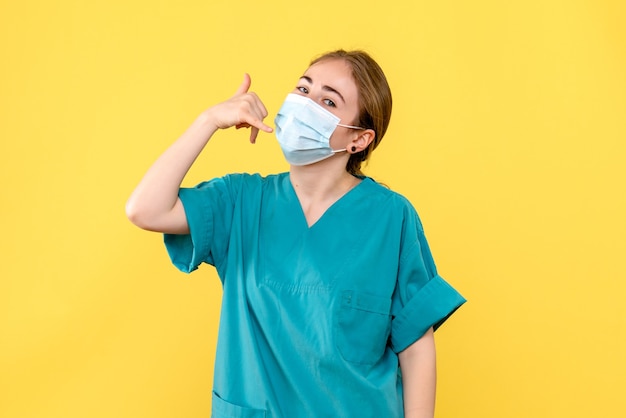 Vue de face femme médecin en masque sur fond jaune virus de la santé pandémique covid