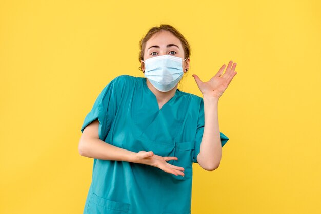 Vue de face femme médecin en masque sur fond jaune virus de la santé pandémique covid