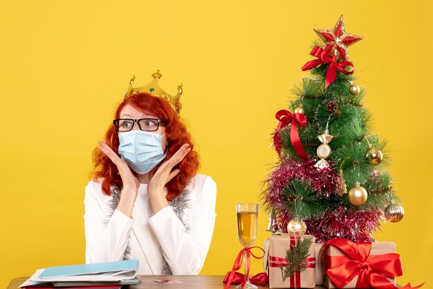 Vue de face femme médecin en masque stérile autour des cadeaux de Noël