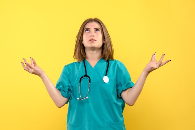 Vue de face femme médecin en méditation pose sur l'espace jaune