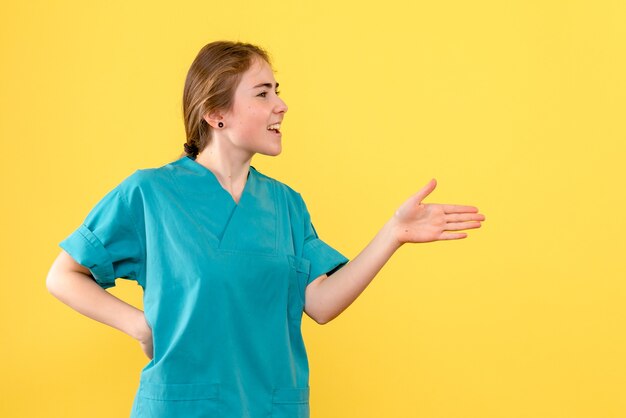 Vue de face femme médecin parler à quelqu'un sur fond jaune virus de couleur de l'hôpital de santé