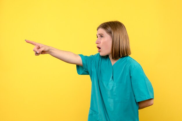 Vue de face femme médecin pointant sur l'espace jaune