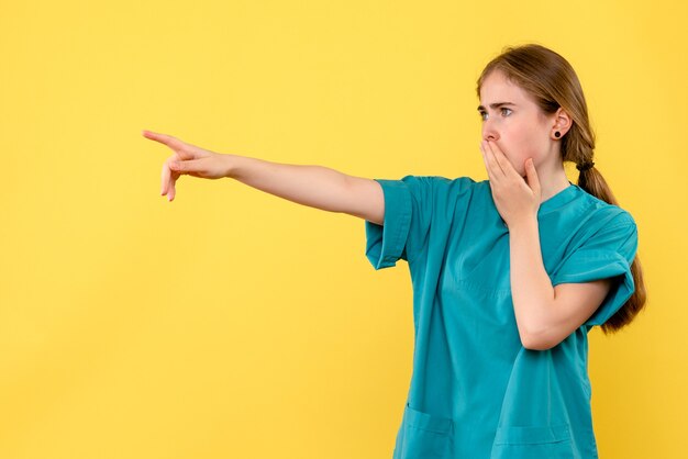 Vue de face femme médecin pointant sur fond jaune émotions santé hôpital medic