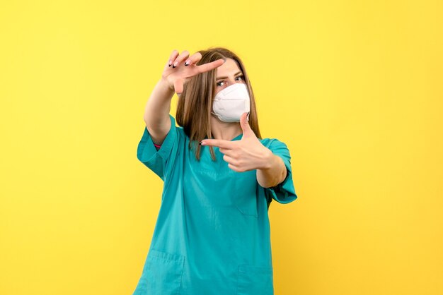 Vue de face femme médecin portant un masque sur l'espace jaune