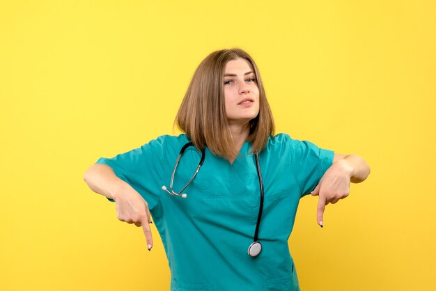 Vue de face femme médecin posant sur l'espace jaune