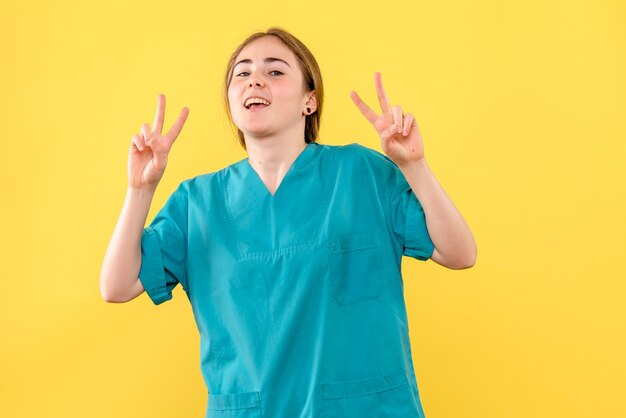 Vue de face femme médecin posant sur fond jaune hôpital émotion médical santé