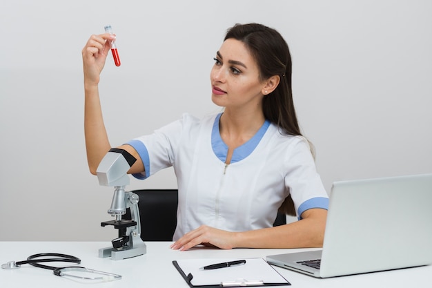 Vue de face femme médecin regardant un échantillon de sang