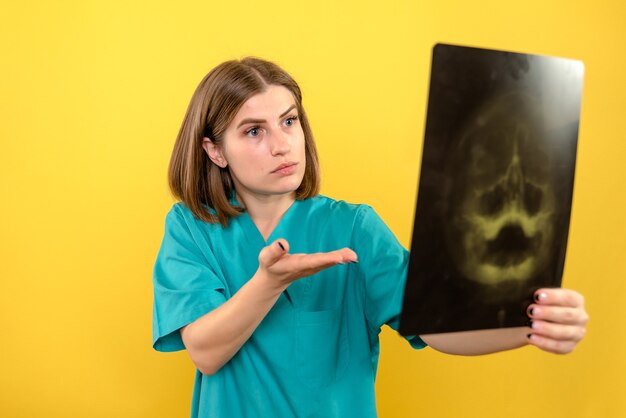 Vue de face femme médecin regardant x-ray sur l'espace jaune