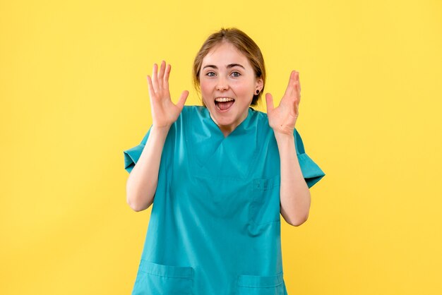 Vue de face femme médecin se réjouissant sur fond jaune émotion médical santé hospitalière