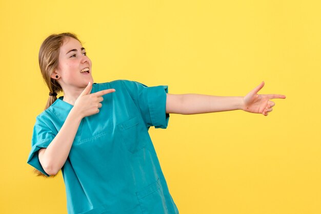 Vue de face femme médecin se réjouissant sur fond jaune émotions de l'hôpital de santé médical