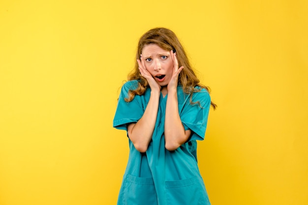 Vue de face de la femme médecin a souligné sur le mur jaune